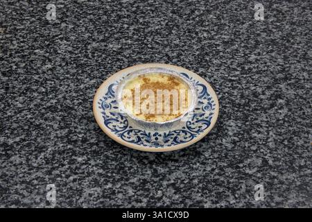 A dessert is sitting on a blue and white plate on a black counter. The dessert is covered in powdered sugar and looks delicious Stock Photo