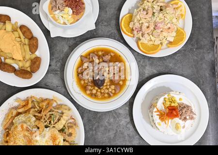 A table with a variety of food, including a cake. The table is set with plates and bowls of different sizes and shapes Stock Photo