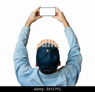 Man in denim jacket and cap holding smartphone above head with raised arms isolated on white Stock Photo