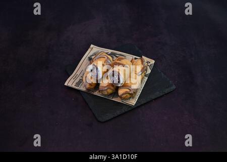 A plate of chocolate covered donuts sits on a black table. The donuts are arranged in a row and appear to be freshly made. The chocolate glaze gives t Stock Photo