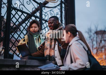Young multicultural people collaborating outdoors in casual attire during early evening Stock Photo