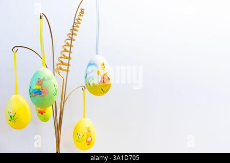 Easter hanging decorations with colorful painted Easter eggs against white background, Easter home decor. Stock Photo