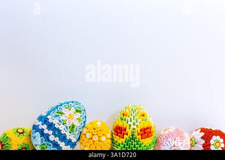 White Easter background with colorful Easter eggs with floral ornaments and origami decorations at the bottom, copy space. Stock Photo