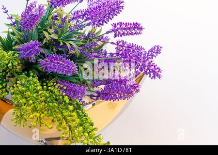 Lavender flowers bouquet composition in a golden vase against white background, spring home decor. Stock Photo