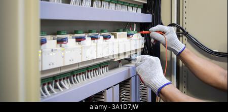 Technicians use multimeter to test or diagnose electrical control devices. Stock Photo