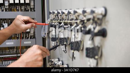 Technicians use multimeter to test or diagnose electrical control devices. Stock Photo
