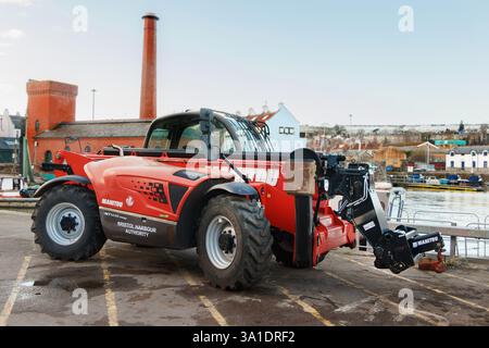 Red Manitou telescopic handler parked at Bristol docks & Harbour with industrial buildings and waterfront in the background Stock Photo