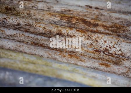 Close-up of a rusty, corrugated roof plate with weathered textures and wavy patterns. The aged metal surface showcases oxidation Stock Photo