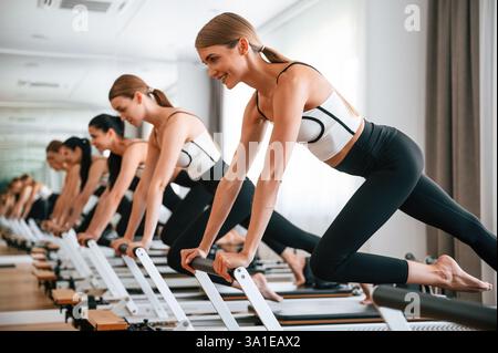 Doing push ups on the special device. Women in fitness center are doing exercises. Stock Photo