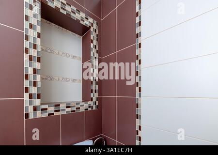 A bathroom with a mirror and a tile wall. The tile wall has a checkered pattern Stock Photo