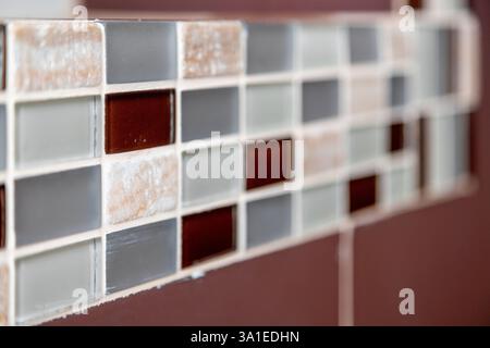 A tile wall with a floral design and a white background. The design is made up of small squares of different colors Stock Photo