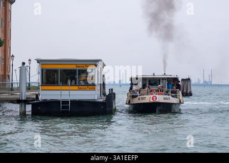 Venice, Italy – 7 October 2023: A vaporetto ferry approaching the floating station of Sacca Fisola, emitting dark smoke Stock Photo