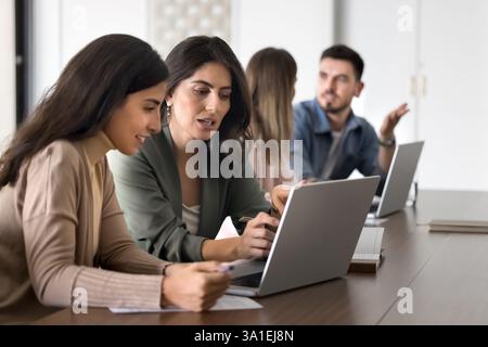Two women colleagues review data on laptop Stock Photo