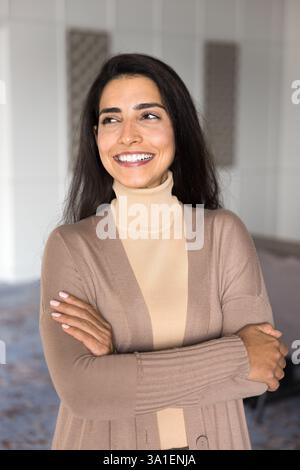 Beautiful Brazilian woman standing with her arms-crossed in workplace Stock Photo