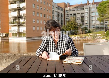 Elderly woman reading a book in an urban park Stock Photo