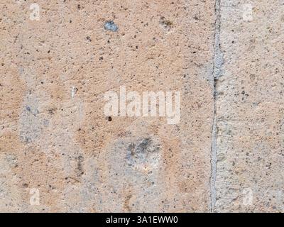 Closeup of a textured beige concrete surface showcases small pebbles fine cracks and delicate white scratches abstract natural background Stock Photo