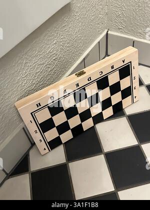 wooden chess board with game pieces on the textured black and white tile table surface floor squares, shapes, smart person play, competition education Stock Photo
