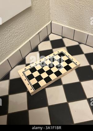 wooden chess board with game pieces on the textured black and white tile table surface floor squares, shapes, smart person play, competition education Stock Photo