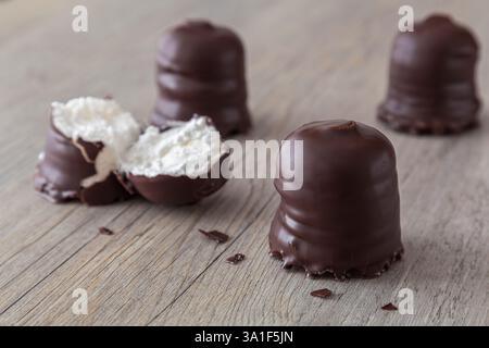 Marshmallows covered in a chocolate flavoured glaze on a wooden table Stock Photo