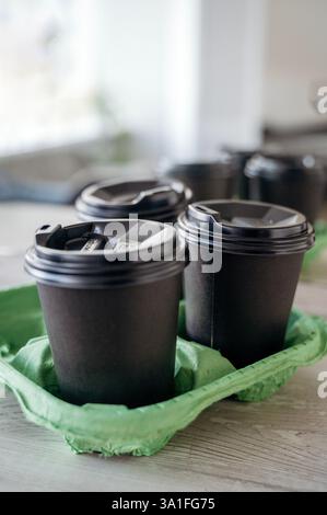 Three black plastic glasses with a drink stand on a light wooden table in the office Stock Photo
