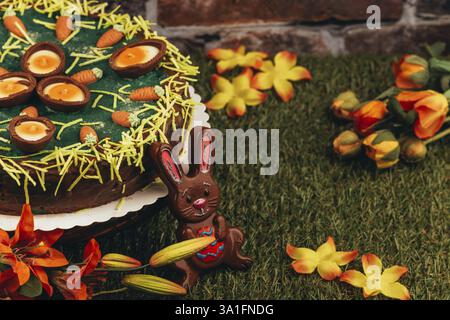 Easter cake with chocolate eggs and carrots, surrounded by flowers and an Easter bunny Stock Photo