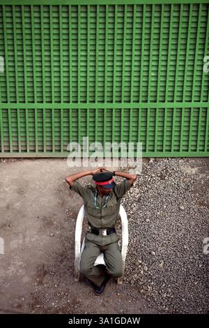 A security guard sitting in front of the gate of the first sale of National Textile Corporations mill lands that took place in Bombay now Mumbai, Maha Stock Photo