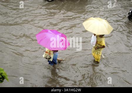 Women with colorful umbrellas making their way through clogged water, heavy rainfall in Vidyavihar in the central suburb of Bombay Mumbai, Maharashtra Stock Photo