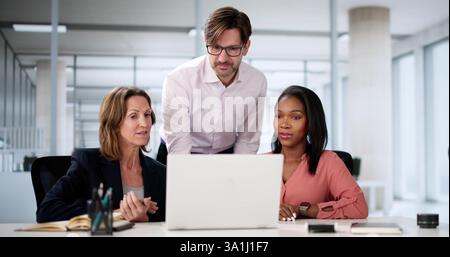 Diverse happy business team collaborating on laptop in office space. Stock Photo