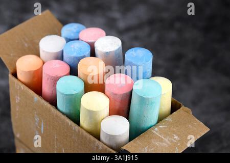 colorful thick street painting chalk sticks filled in a cardboard box on black background Stock Photo