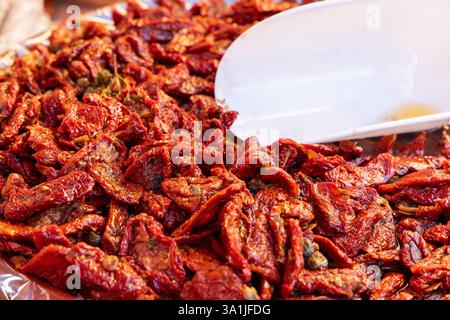 Heap of sun-dried tomatoes soaked in oil and spices rich red color and soft wrinkled texture glisten under the light Stock Photo