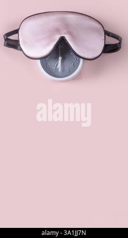 Light pink sleeping mask and alarm clock isolated on pastel pink background. World sleep day concept Stock Photo