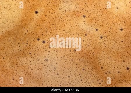 A close-up of creamy coffee foam, showcasing the delicate texture and rich, frothy surface, capturing the essence of a freshly brewed cup of espresso Stock Photo