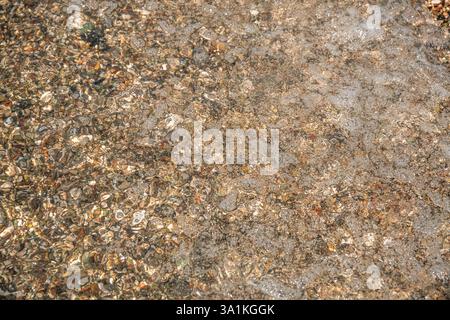 multi-colored stones under water on the sea, river. Natural background of stones, glare on the water Stock Photo