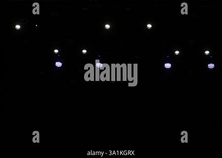 Empty stage lighting setup with red, yellow, and blue spotlights shining down, creating a dramatic atmosphere on a dark backdrop, perfect for concert Stock Photo