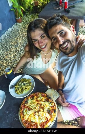 Tourists taking a selfie while having lunch with pizza and pasta in a restaurant in siargao island, philippines Stock Photo
