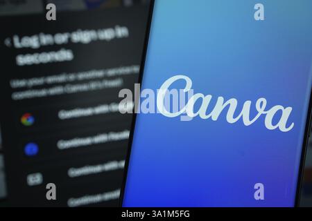 Canva logo is displayed on a smartphone screen, with the canva login page visible on a computer screen in the background Stock Photo