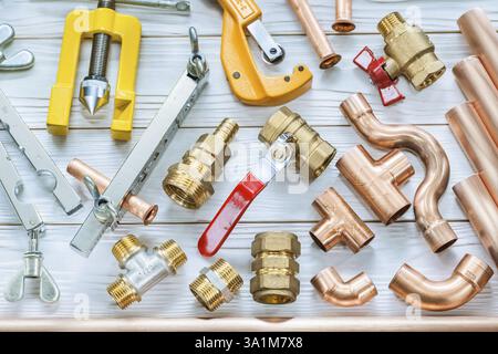 Plumbing tools copper pipes pipe cutter fittings valwes flaring clamps on white wooden boards Stock Photo