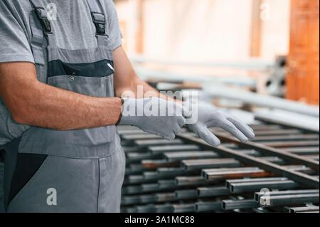 Wearing the gloves. Close up view of man that is working at the factory. Stock Photo
