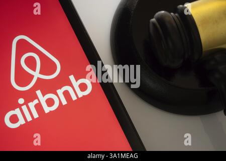 A close up of an iPad screen displaying the airbnb logo alongside a judge's gavel Stock Photo