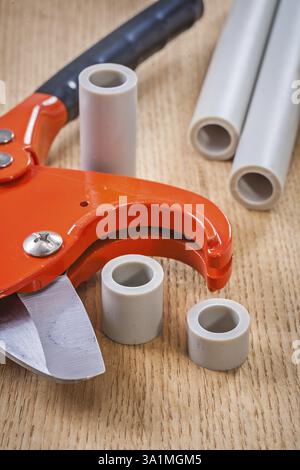 Pipe cutter and cutted pipes on wooden board composition Stock Photo