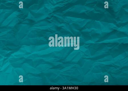 This captivating artwork features a close-up of crumpled turquoise paper, revealing intricate textures and shadows. Stock Photo