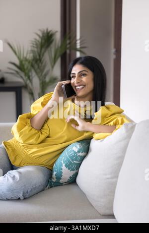 Pretty Indian woman lead pleasant conversation with friend on smartphone Stock Photo