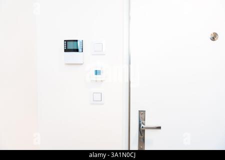 Smart home control panel and thermostat on white wall in modern interior Stock Photo