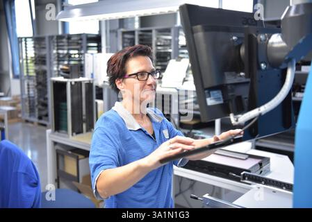woman works in the production of a factory for electronics - operation of a production machine Stock Photo