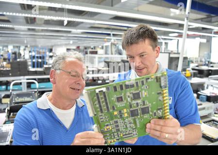 engineer working on a machine for assembly and production of semiconductor boards in an industrial plant Stock Photo