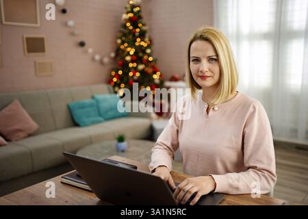 Working from home with holiday spirit in a cozy living room decorated for Christmas Stock Photo