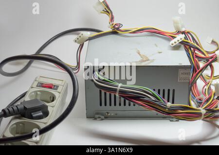 computer ATX non-modular power supply unit front side with ventilation openings, with directly connected colored connectors for drives, at the surge p Stock Photo