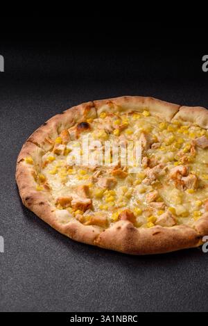 Hawaiian pizza with chicken, pineapple, corn and cheese on dark concrete background Stock Photo