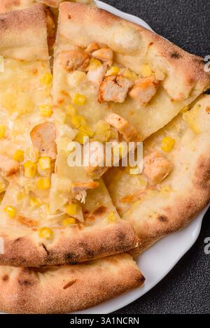 Hawaiian pizza with chicken, pineapple, corn and cheese on dark concrete background Stock Photo