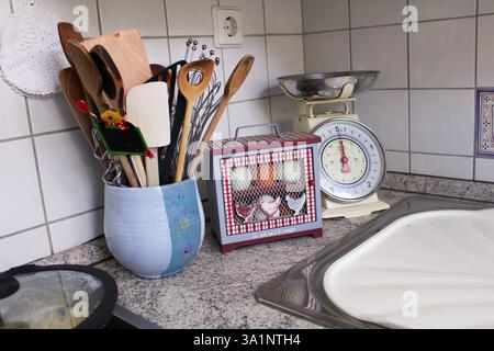 Charming country kitchen with a vintage egg storage box, rustic utensils, and a retro scale, creating a welcoming farmhouse-style ambiance. Stock Photo